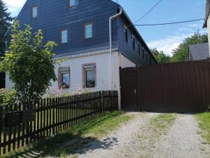 a house with a black roof and a fence at Ferienwohnung am Chemnitztalradweg in Taura