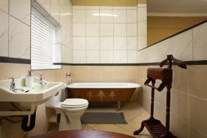 a bathroom with a tub and a toilet and a sink at The Old Watchmakers Guest House in Bethulie