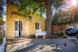 a grill in front of a yellow house with a tree at The Old Watchmakers Guest House in Bethulie +19 photos