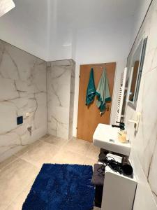 a bathroom with a sink and a shower with a blue rug at Apartment 2 in Golling an der Erlauf in Petzenkirchen +10 photos