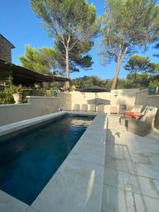 a swimming pool in a backyard with chairs and trees at LA BASTIDE De La Colline in Cavaillon