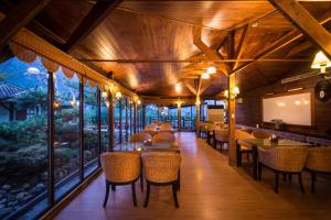 a dining room with tables and chairs and windows at Wulai SungLyu Hot Spring Resort in Wulai