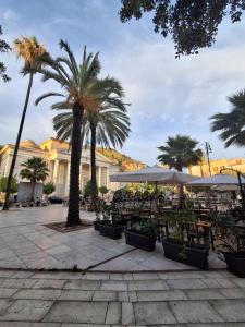 a courtyard with palm trees and tables and umbrellas at Casa Vacanze a Piazza Garibaldi in Terracina