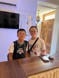two young boys standing next to a wooden table at GUZAL Boutique Hotel in Bukhara