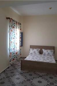 a bedroom with a bed and a window with curtains at Studio Cosy Mde Comores 