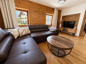 a living room with a leather couch and a table at Fritz Alpchalets - Haus Lechtal in Vorderhornbach