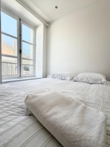 a white bed in a white room with a large window at Excellence 2 bedrooms in Saint-Pierre-le-Vieux
