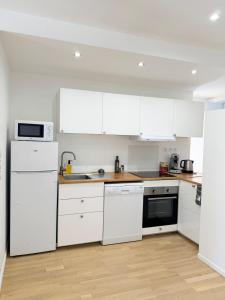 a white kitchen with white appliances and a wooden floor at Excellence 2 bedrooms in Saint-Pierre-le-Vieux