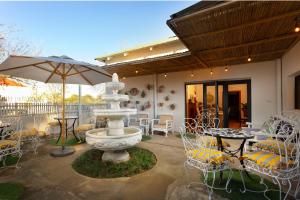 a patio with a fountain and tables and chairs at The Old Watchmakers Guest House in Bethulie