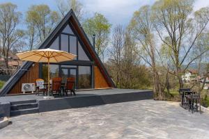 a house with a thatched roof with chairs and an umbrella at AVA Chalet with Jacuzzi in Sinaia