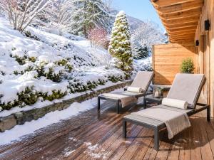 a deck with two chairs and snow covered trees at Chalet Greystone in Brides-les-Bains