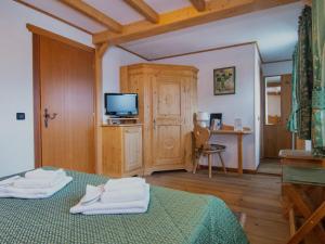 a bedroom with two beds and a tv and a desk at Alla Frasca Verde in Lauco