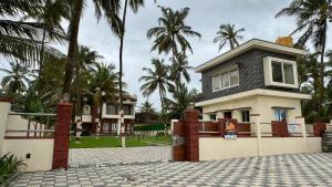 a house with palm trees in front of it at CASANADA Sea View Suite in Malpe