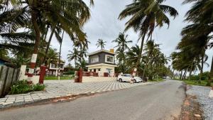 a white car parked in front of a house with palm trees at CASANADA Sea View Suite in Malpe