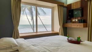a bedroom with a large window with a view of the ocean at CASANADA Sea View Suite in Malpe