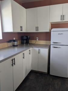 a kitchen with white cabinets and a white refrigerator at Le Pignon Douillet in Sainte-Anne-des-Monts