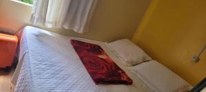 a bedroom with a white bed with a red pillow on it at Joy Apartamento completo in Salvador