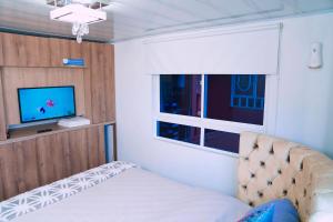 a bedroom with a bed and a tv and a window at Apartamento THEMIS Tocancipa in Bemposta