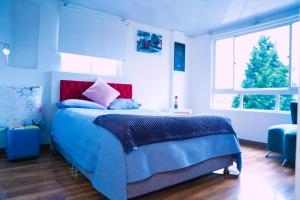 a bedroom with a blue bed with a red headboard at Apartamento THEMIS Tocancipa in Bemposta +78 photos
