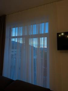 a bedroom with a large window with white curtains at Старий Дуб in Mizhhirya