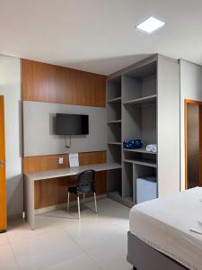 a bedroom with a bed and a desk and a tv at Rosmarry Hotel in Colinas do Tocantins