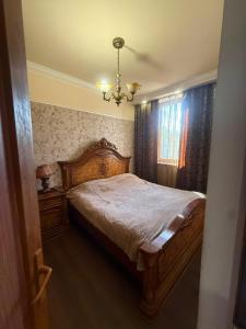 a bedroom with a wooden bed and a chandelier at home 4 room in Yerevan