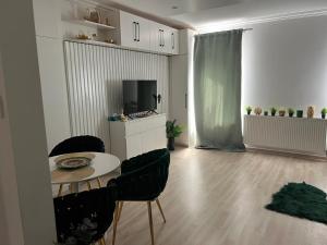 a living room with a table and chairs and a television at Picúr és Manó Apartmanjai- Picúr Apartman és Manó Apartman in Baja