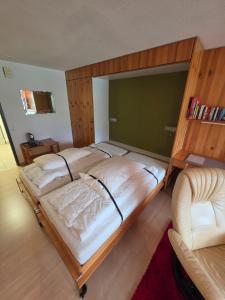 a bedroom with a large bed and a chair at Utoring Acletta B 27 in Disentis