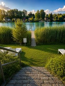 ein Gehweg neben einem See mit zwei Bänken in der Unterkunft Ausee Camping in Blindenmarkt