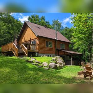 a large log cabin with a porch and a yard at Chalet Le Boisé SPA et Rivière in Brownsburg