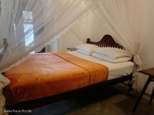 a bedroom with a canopy bed with white sheets and pillows at WG Villa Wathurugama in Kannimahara