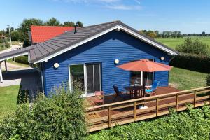 a blue house with a deck with an umbrella at Haus Freija in Sehestedt