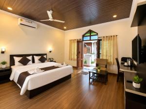 a bedroom with a large bed and a living room at Palm Escape Beach Resort in Baga