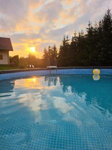 a large swimming pool with a sunset in the background at Słoneczna Polana in Solina