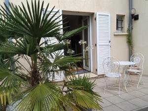 a patio with a table and chairs and a palm tree at Orée de Villevert in Senlis +7 photos