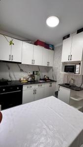 a kitchen with white cabinets and a white table at Квартира посуточно in Balqash