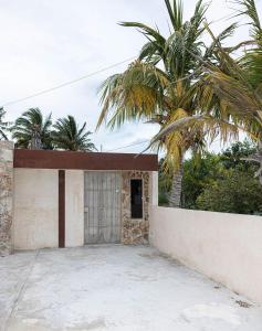 a building with a gate and a palm tree at Paz y Mar in Chelem