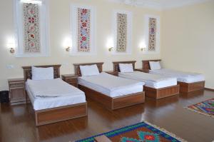 three beds in a room with wooden floors and windows at Hostel East Star Khiva in Khiva