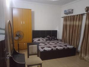 a bedroom with a bed and a chair at Service Apartment in Okunola