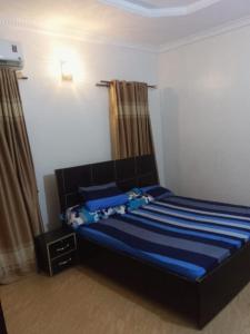 a bedroom with a bed with blue sheets and curtains at Service Apartment in Okunola