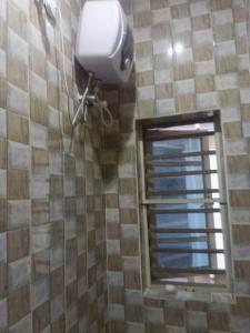 a bathroom with a hair dryer and a window at Service Apartment in Okunola