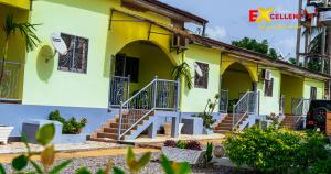 a yellow house with stairs in front of it at Appart meublé Excellentia Edea in Edéa
