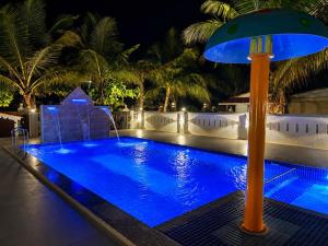 a large blue pool with a umbrella next to it at Palm Escape Beach Resort in Baga