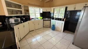 a kitchen with white cabinets and a black refrigerator at Amazing Antigua Getway in Bolans +13 photos