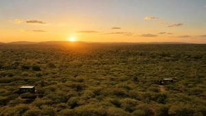 an aerial view of a field with the sunset in the background at Mudhouse Zululand in Hluhluwe