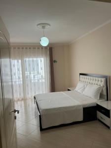 a bedroom with a white bed and a window at Elsuarha Apartment in Pogradec