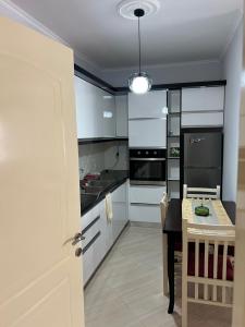 a kitchen with white cabinets and a black table at Elsuarha Apartment in Pogradec +9 photos