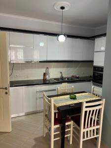 a kitchen with white cabinets and a table and chairs at Elsuarha Apartment in Pogradec
