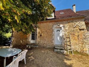 a small brick building with a table and a ladder at La Maison de Renée in Sainte-Eulalie-dʼAns