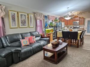 a living room with a black leather couch and a kitchen at Home Sweet Home in Red Deer